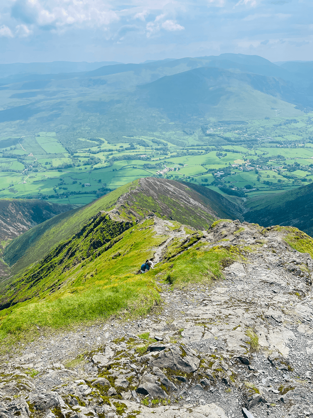 Walker on a rocky ridge path high above the Lake District
